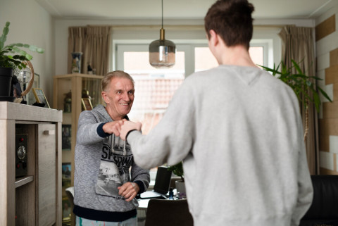 Tienerjongen groet oudere man met een vuist